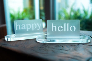 Acrylic Card Holder shown with custom engraved acrylic cards that read "happy" and "hello".